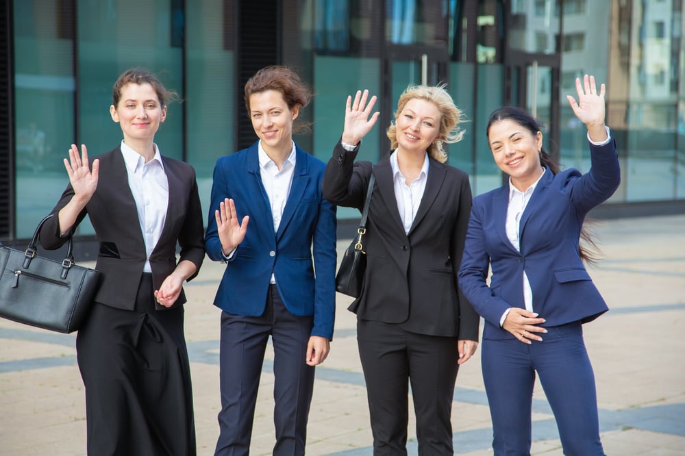 happy-business-ladies-team-waving-hello-standing-together-near-office-building-looking-camera-smiling-medium-shot-front-view-businesswomen-group-portrait-concept